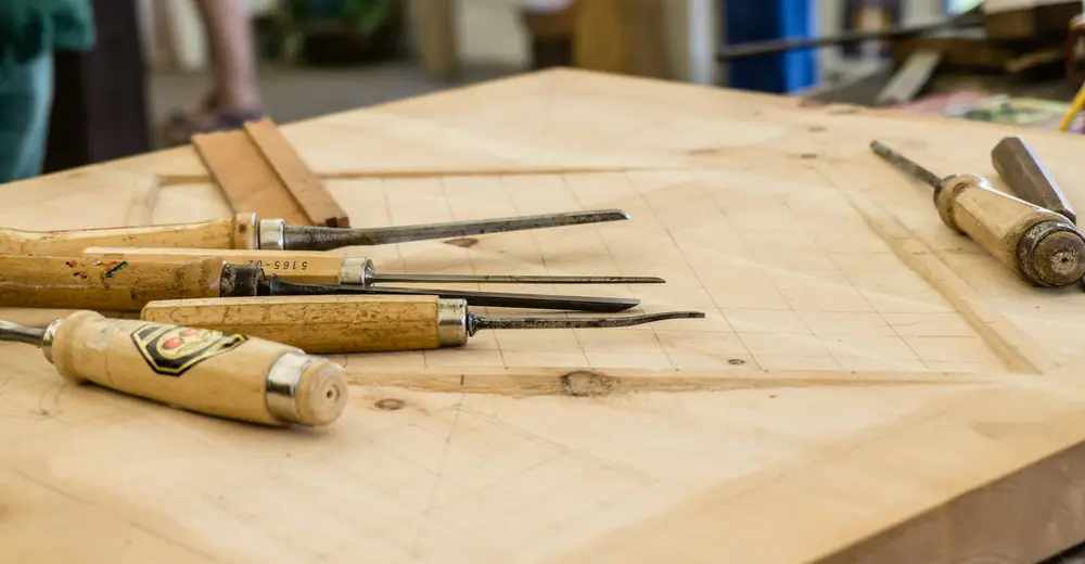 Stechbeitel mit Holzgriffen, ausgelegt auf einer hellen Werkbank aus Holz