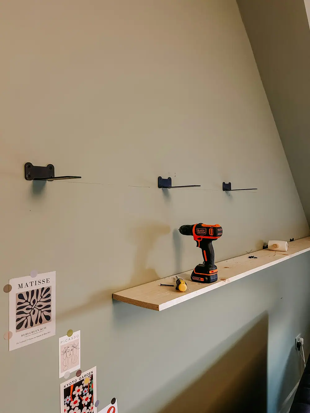 Unsichtbare Regalträger an einer hellen Wand, auf dem fertigen Regalbrett liegt ein Akkuschrauber